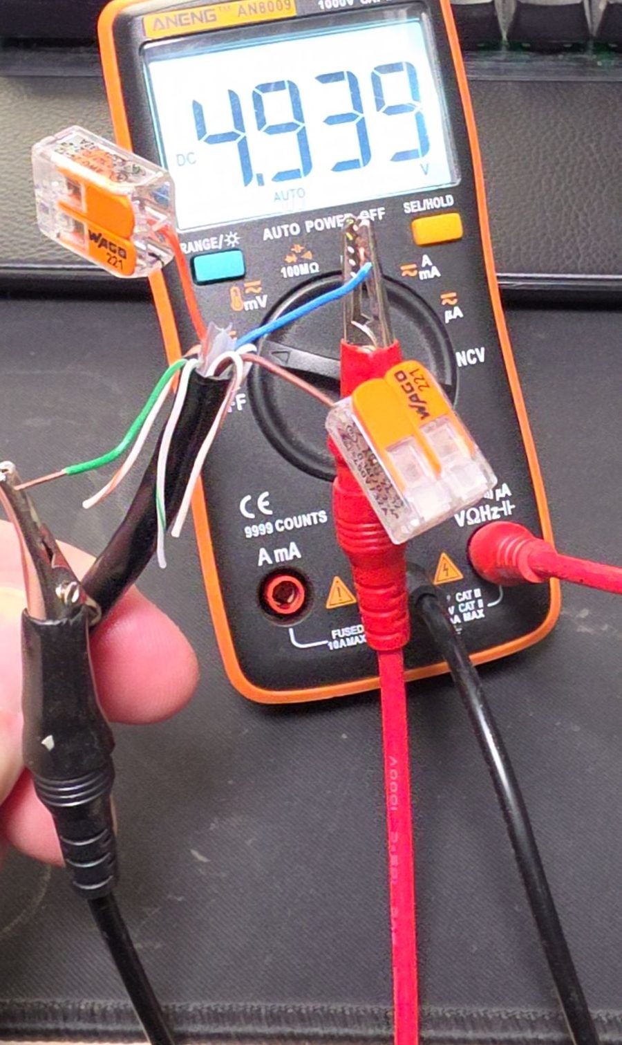 Multimeter showing 4.939 V measured between the green and blue wires